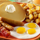 Pancakes, potatoes, bacon, and eggs on an orange plate